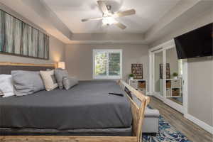 Master Bedroom featuring wood finished floors, a ceiling fan, a tray ceiling, and access to outside