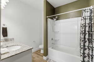 Full bath featuring vanity, shower / bath combo with shower curtain, and light wood-type flooring