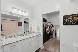 Bathroom featuring vanity, a walk in closet, curtained shower, dark carpet, and dark wood-style floors
