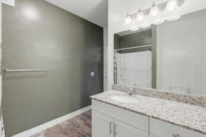 Bathroom featuring vanity, light wood-style flooring, and curtained shower