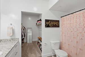 Full bathroom featuring vanity, curtained shower, a spacious closet, and dark carpet
