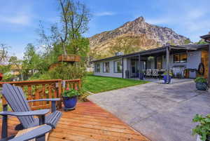 Wooden terrace featuring grilling area, a yard, a patio area, and a mountain view