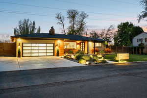 View of front of house with a garage, concrete driveway, and a chimney