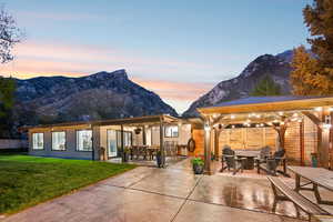 Rear view of property featuring outdoor dining area, a patio area, and a mountain view