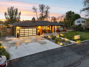 View of front of home featuring a chimney, driveway, a garage, and a porch