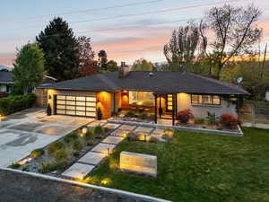 View of front facade with concrete driveway, a chimney, a garage, brick siding, and a shingled roof