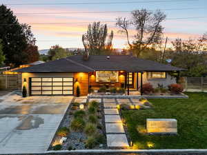 View of front facade featuring concrete driveway, an attached garage, a chimney, and brick siding