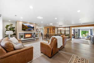 Living room with a glass covered fireplace, light wood-type flooring, and recessed lighting