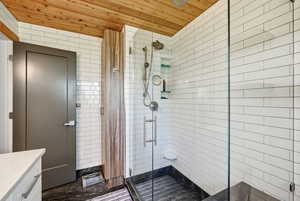 Full bathroom with vanity, a stall shower, wooden ceiling, and tile walls