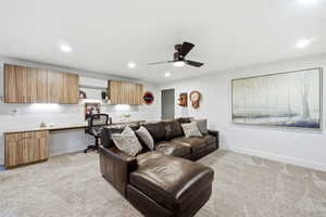 Living area featuring light carpet, ceiling fan, built in study area, and recessed lighting