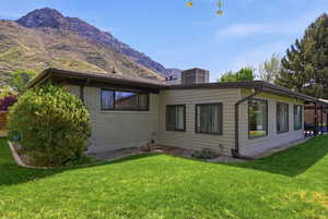 Back of house with brick siding, a yard, a patio, and a mountain view