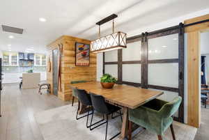 Dining area with a barn door, recessed lighting, and light wood-type flooring