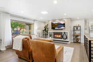 Living area featuring light wood-style floors, a glass covered fireplace, and recessed lighting