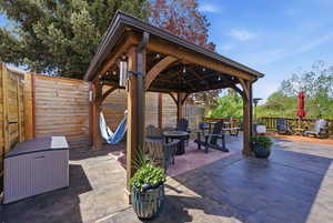 Fenced backyard featuring an outdoor fire pit, a patio, and a gazebo