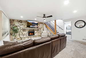 Living area featuring a ceiling fan, carpet floors, a stone fireplace, and recessed lighting