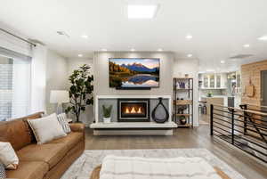 Living room featuring light wood-style flooring, a glass covered fireplace, and recessed lighting