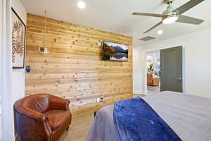 Bedroom featuring a ceiling fan, recessed lighting, wood walls, and wood finished floors