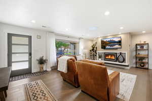Living room featuring hardwood / wood-style flooring, recessed lighting, and a glass covered fireplace