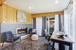Office area featuring wooden walls, a glass covered fireplace, and recessed lighting
