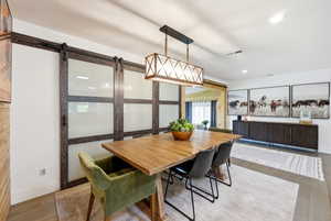 Dining area with light wood-style flooring and a barn door
