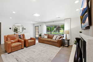 Living room with light wood-style flooring, recessed lighting, and a fireplace