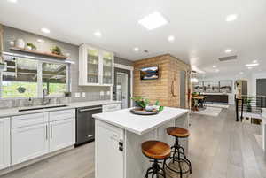 Kitchen with white cabinets, a breakfast bar area, a center island, and light wood finished floors