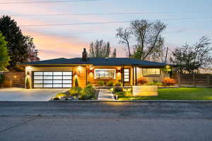 View of front facade featuring concrete driveway, a garage, a chimney, brick siding, and covered porch