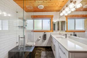 Full bath with vanity, tile walls, a shower stall, and wooden ceiling