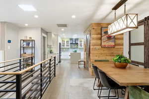 Dining space with light wood-style floors, recessed lighting, and a barn door