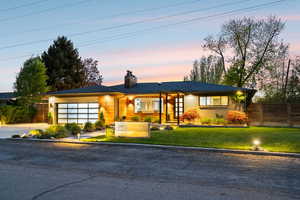 View of front of home with a garage, a chimney, brick siding, and concrete driveway