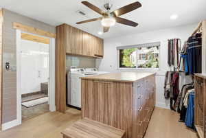 Laundry area featuring light wood-type flooring, cabinet space, recessed lighting, ceiling fan, and separate washer and dryer