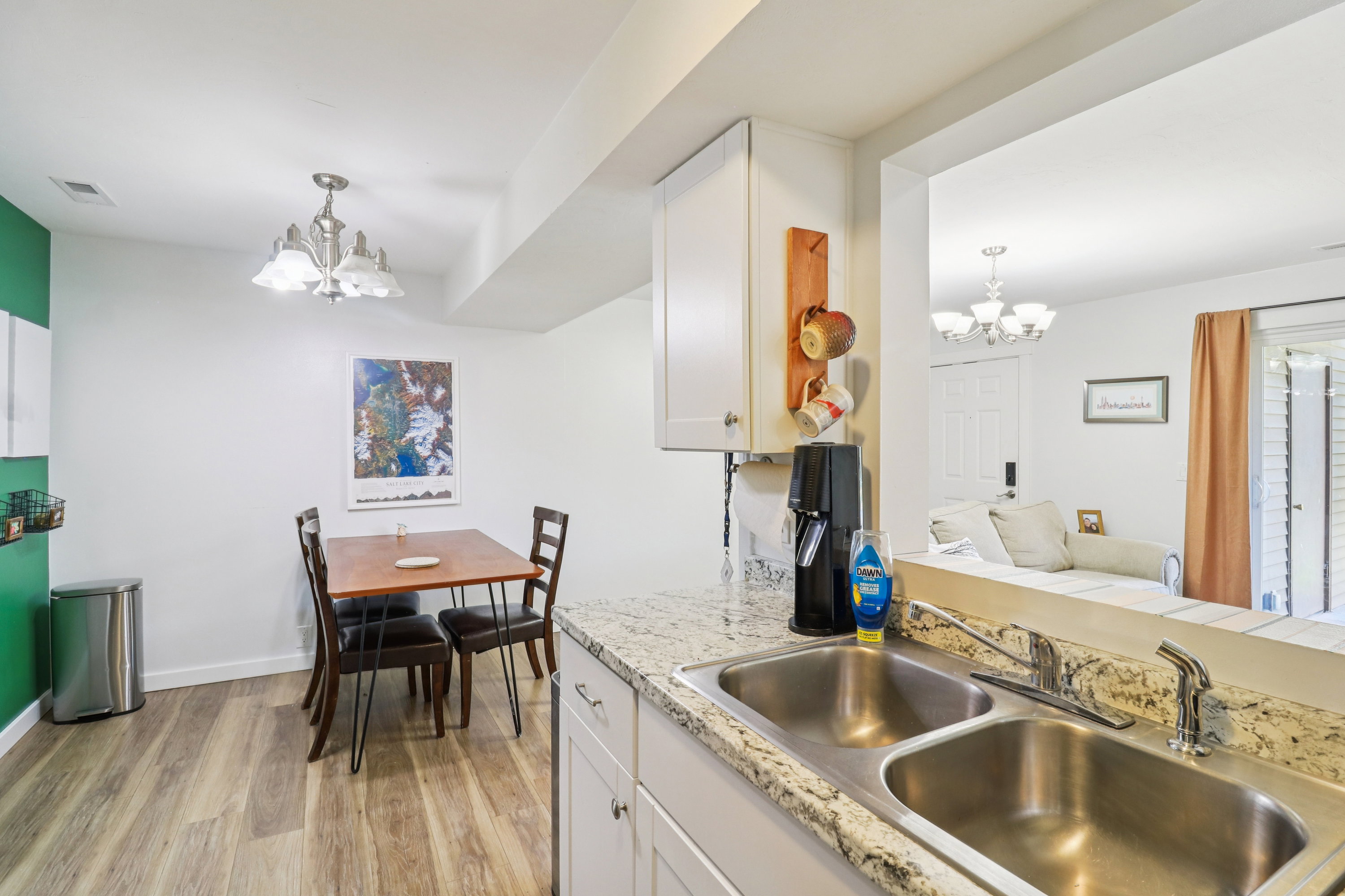 Kitchen with suspended lighting, light wood-type flooring, and white cabinetry