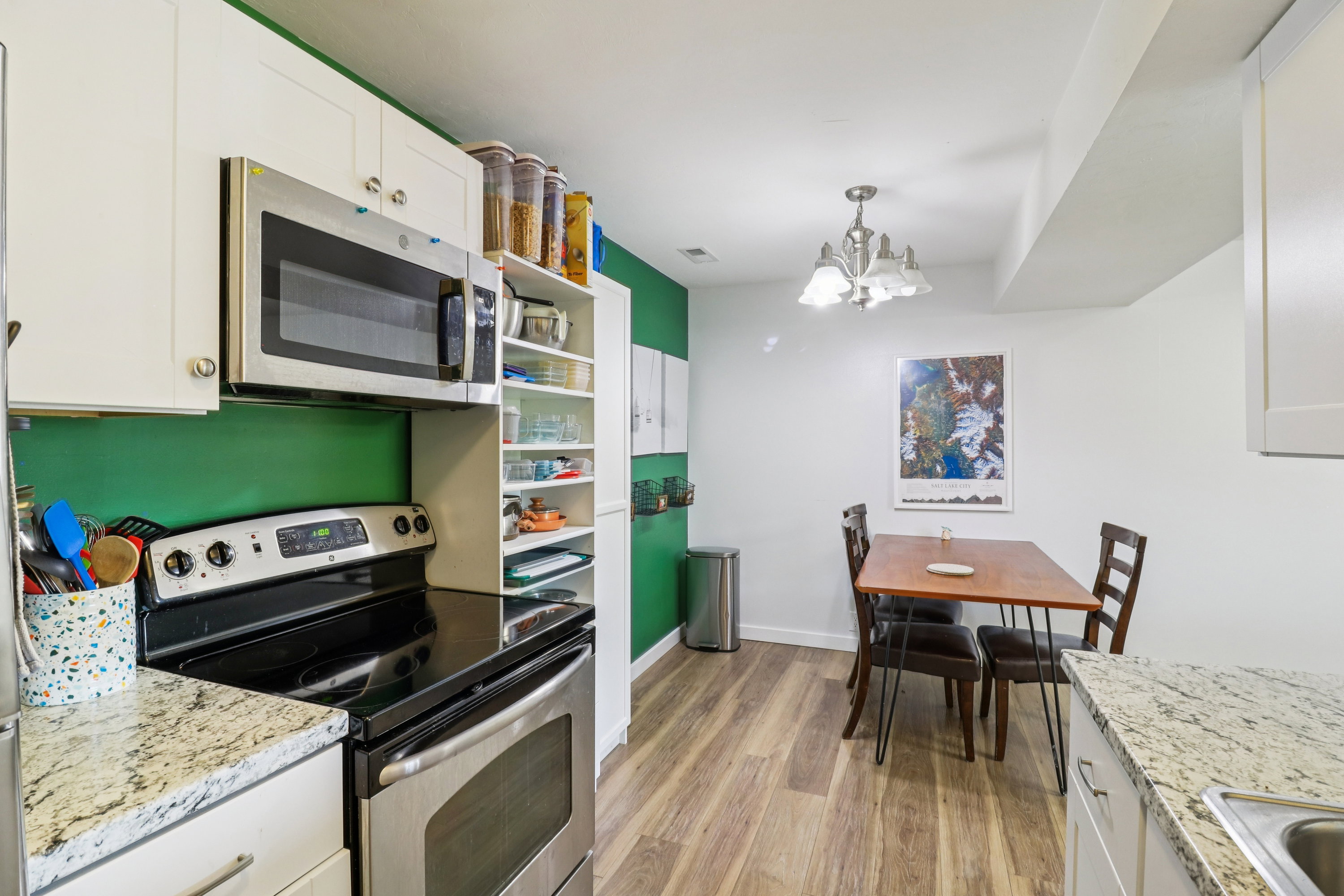 Kitchen with stainless steel appliances, white cabinets, and suspended lighting