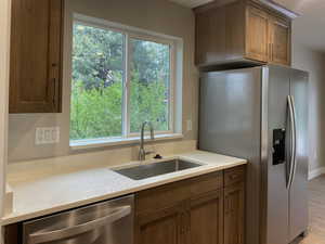 Kitchen featuring stainless steel appliances, light stone countertops, wood finish cabinetry, and light wood-type flooring