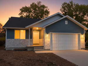 Ranch-style home featuring stone siding, an attached garage, and concrete driveway