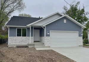 Ranch-style home with stone siding, a garage, and driveway