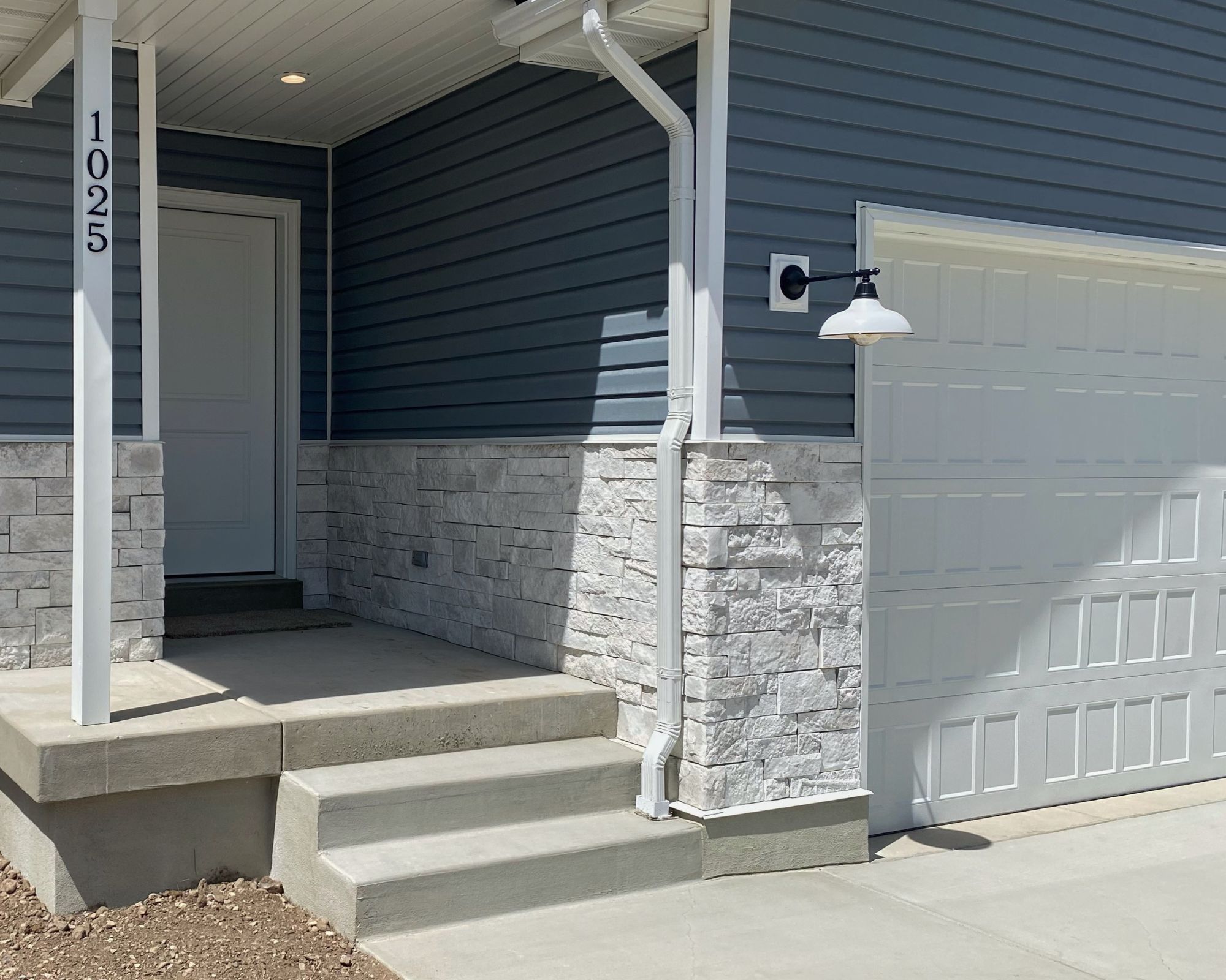 Entrance to property with stone siding, a garage, and a porch
