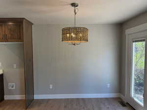 Unfurnished dining area featuring light wood-style floors, a chandelier, and a textured ceiling