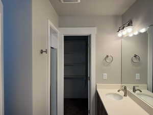 Full bathroom with vanity and a walk in closet