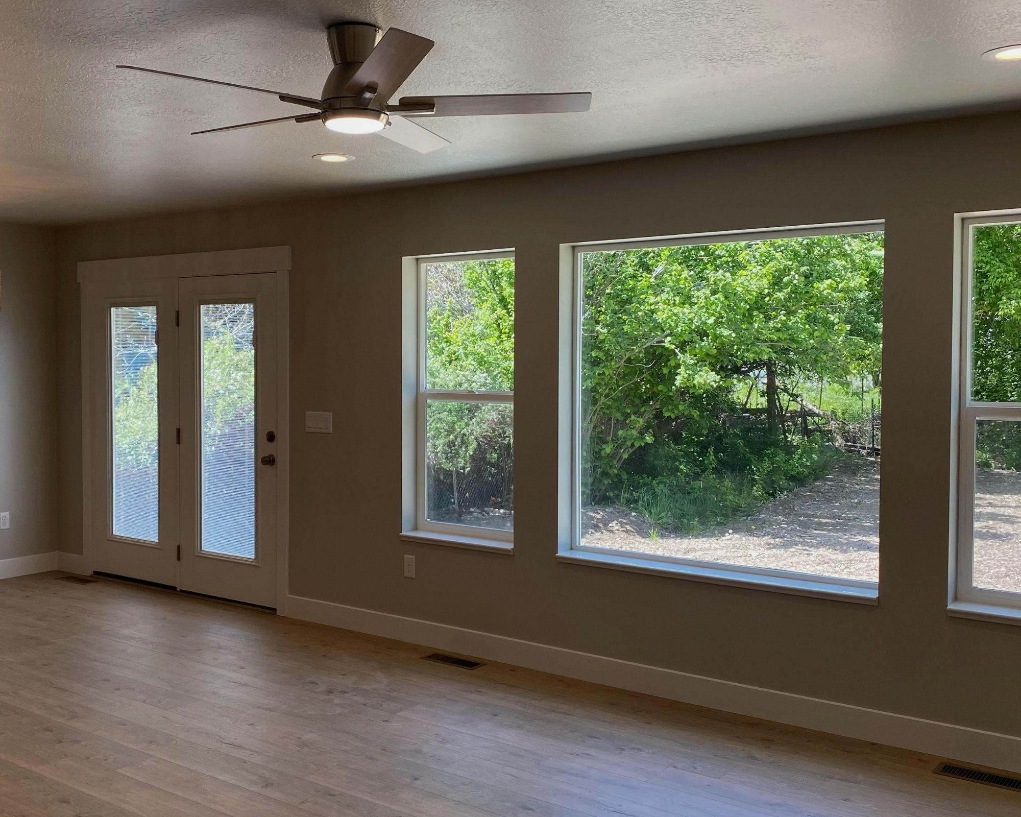 Empty room featuring a textured ceiling, ceiling fan, and light wood-style flooring