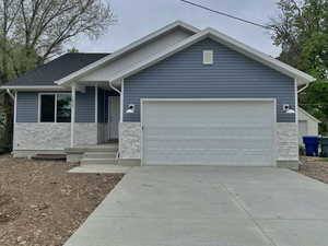 Single story home featuring stone siding, driveway, and a garage