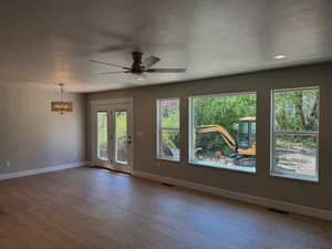 Spare room featuring a textured ceiling, a ceiling fan, light wood-style flooring, and a chandelier