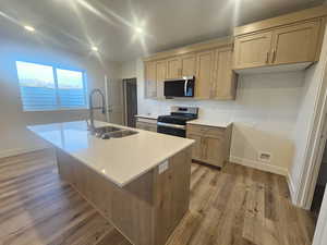 Kitchen featuring stainless steel appliances, an island with sink, light wood-style floors, recessed lighting, and light wood finish cabinets