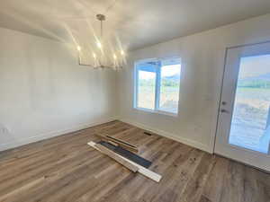 Unfurnished dining area featuring a chandelier and dark wood-style flooring