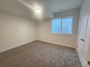 Unfurnished bedroom with dark colored carpet and a closet