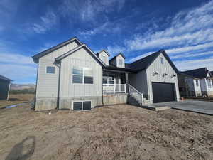 Modern inspired farmhouse featuring a porch, board and batten siding, driveway, and a garage