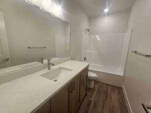 Full bathroom with vanity, dark wood-style floors, and bathing tub / shower combination