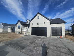 Modern farmhouse style home with an attached garage, concrete driveway, board and batten siding, and a porch