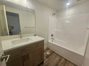 Bathroom with vanity, dark wood-type flooring, and shower / tub combination