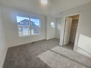 Unfurnished bedroom with a walk in closet and carpet flooring